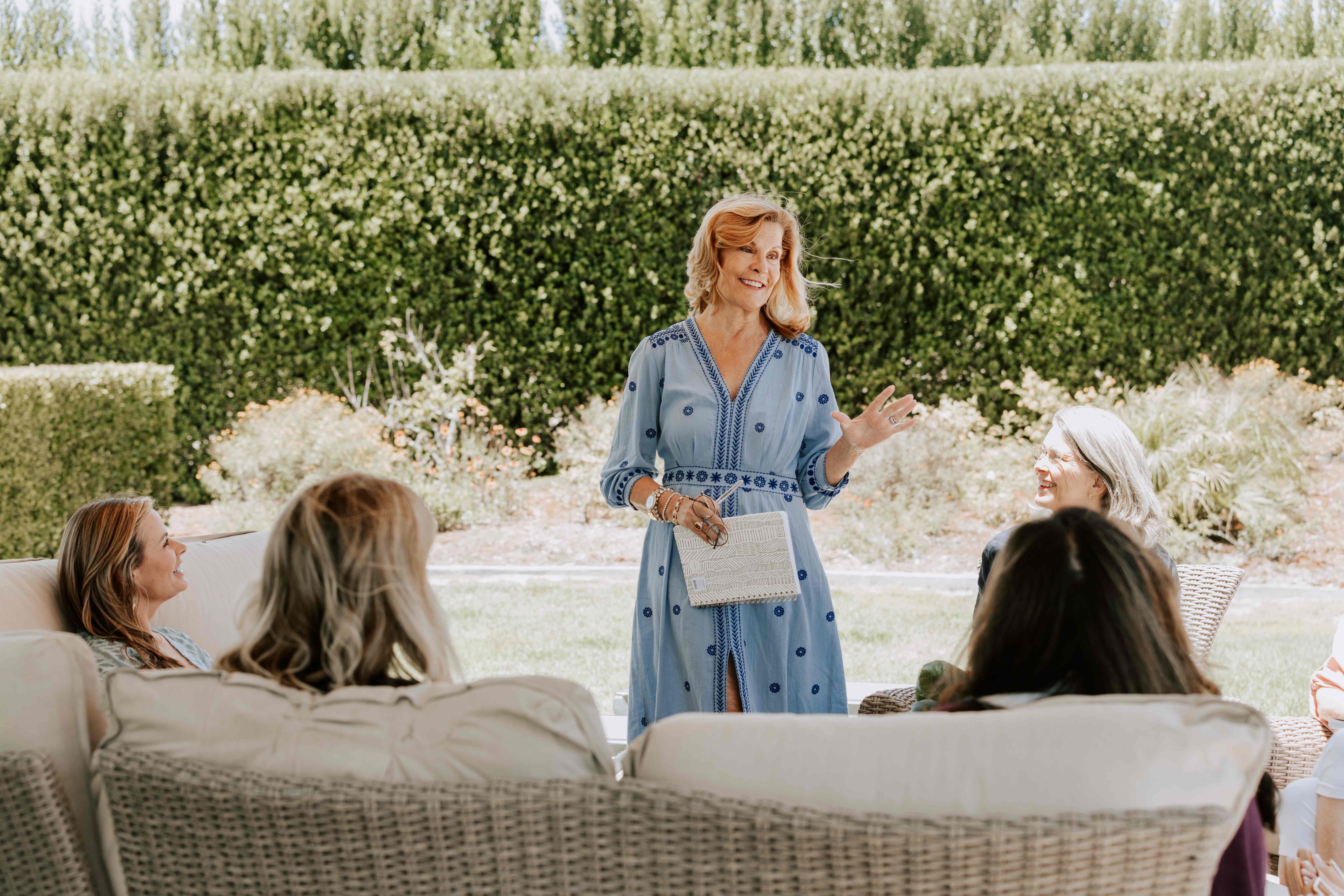 A group of women seated in a circle in conversation at a golden-hour garden retreat