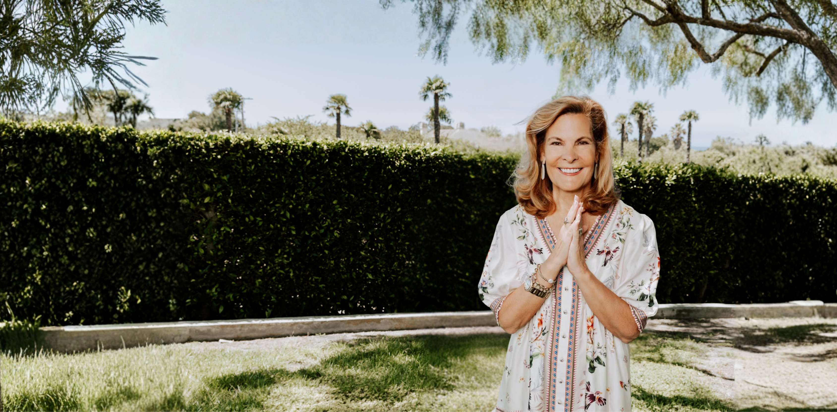 Leighanne Champion smiling with hands pressed together in a sunlit garden